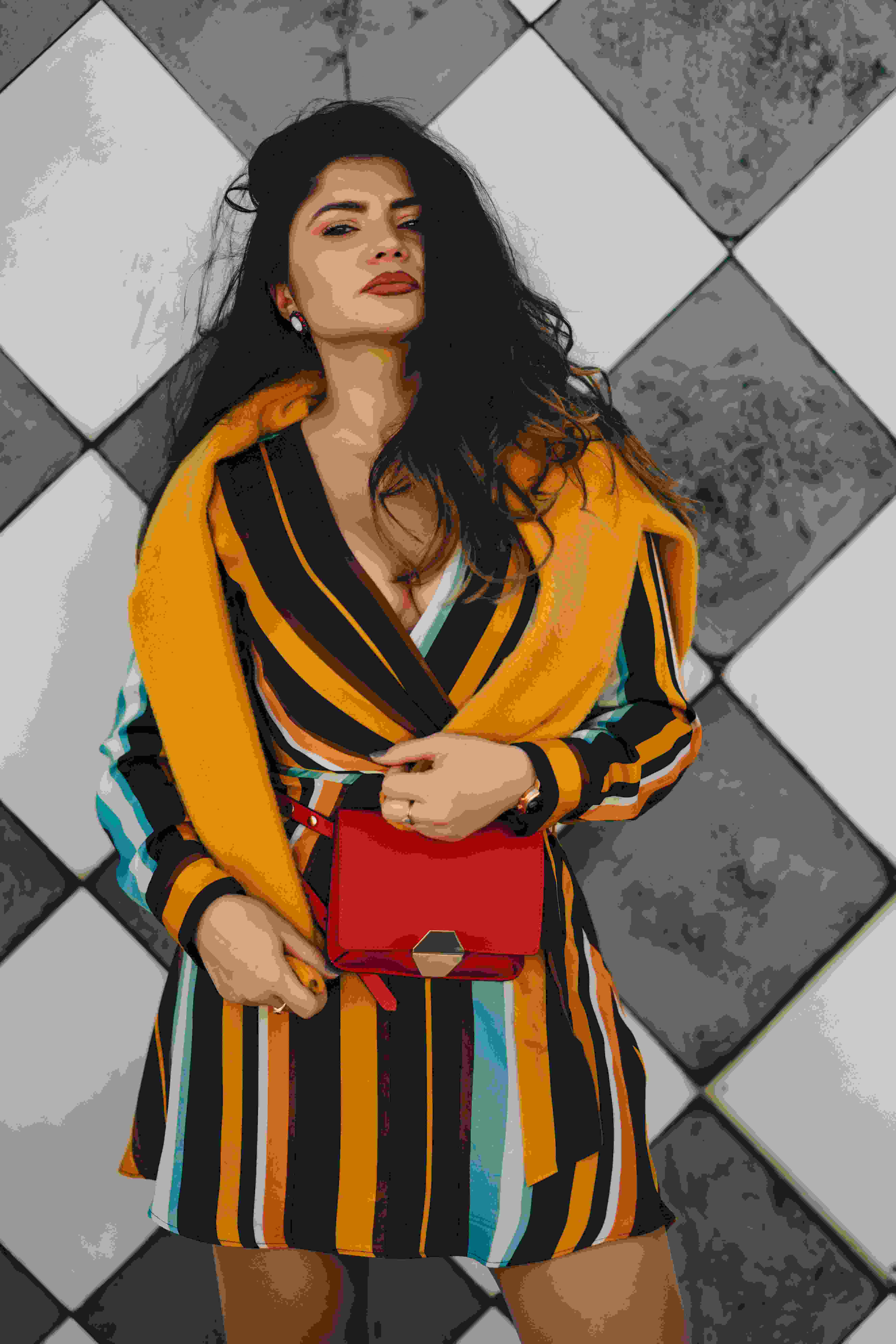 picture, woman in a striped outfit posing in front of a checked pattern wall