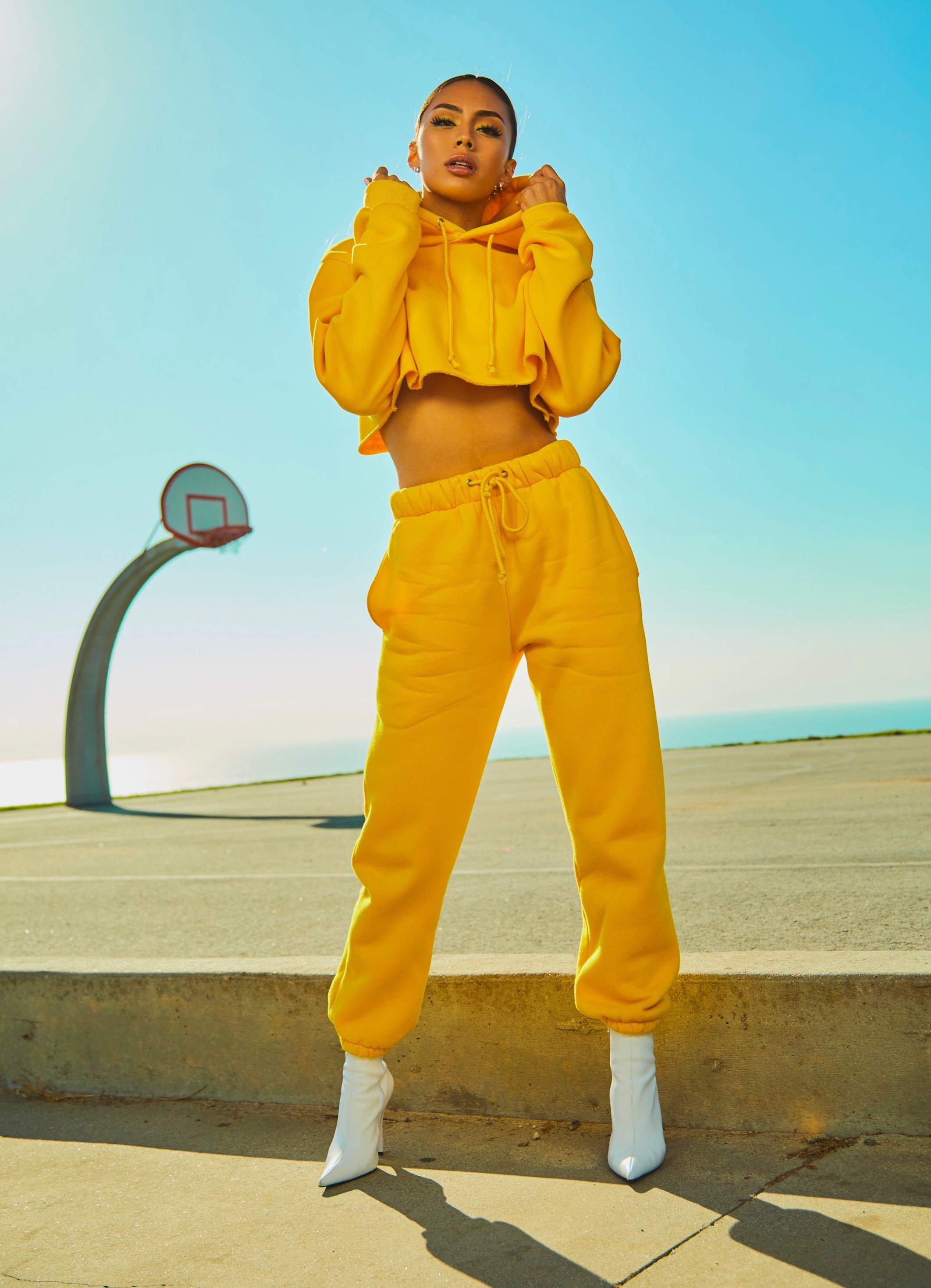 picture, woman in a yellow tracksuit on a basketball field by the beach